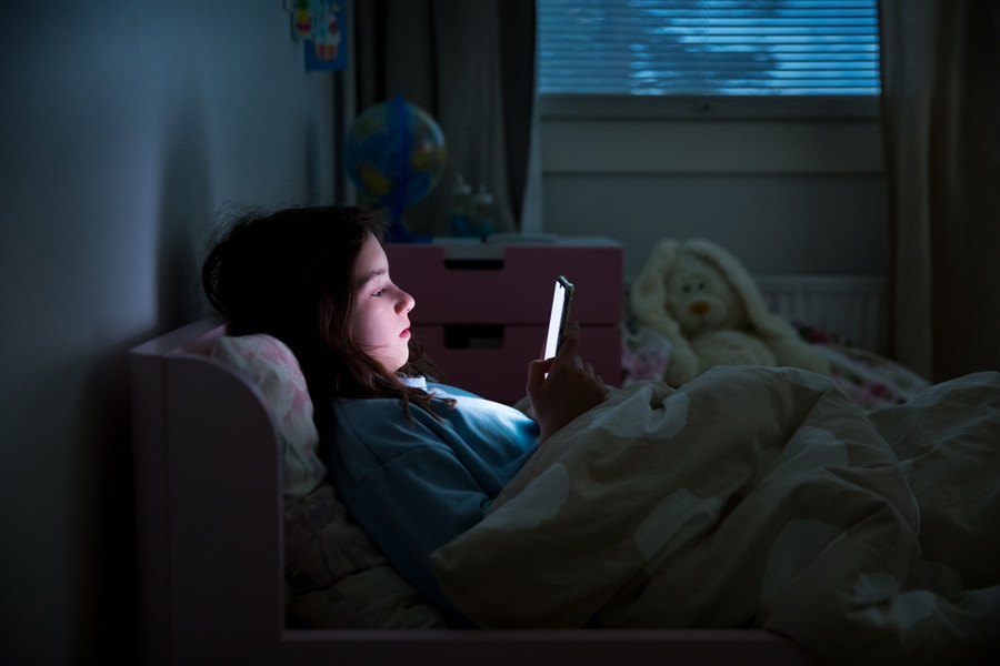 Kids with phones in bedroom at night